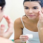 Body care. Woman applying cream on face